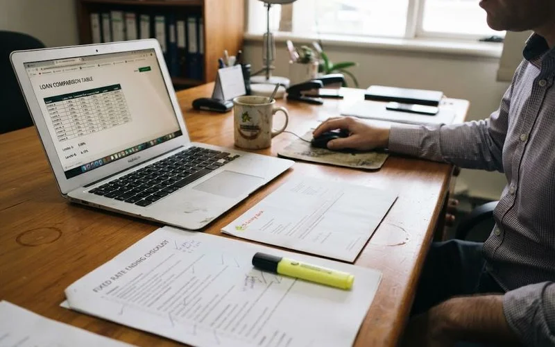 A calendar with a circled date marked fixed rate ends, next to a laptop showing loan comparison options